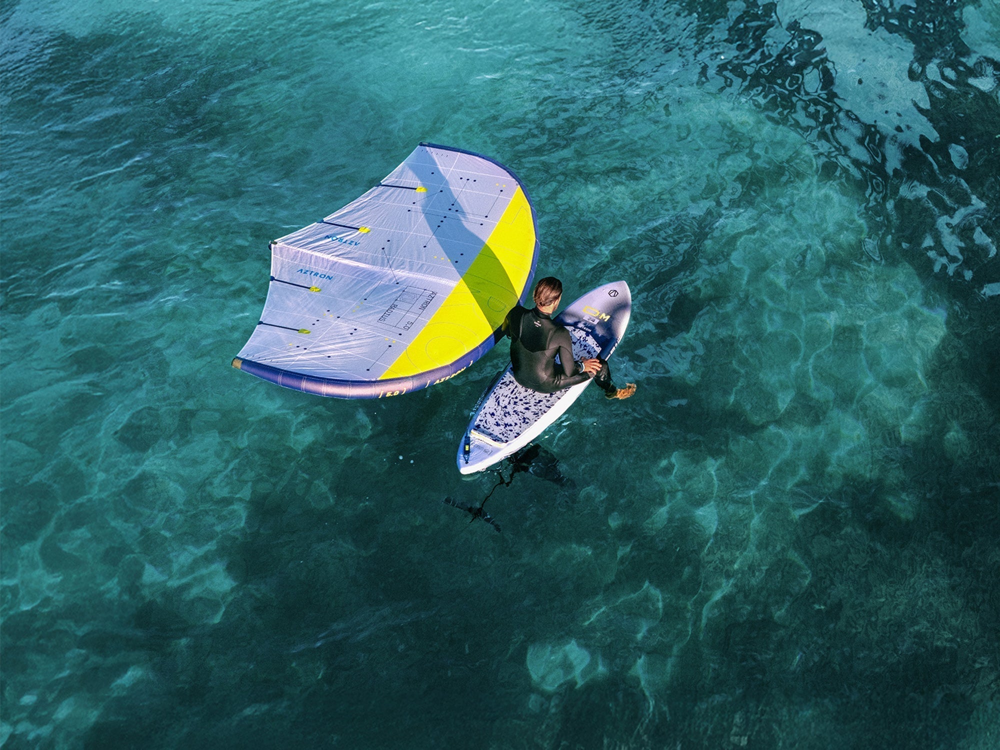 Denizde windsurf yapan kişi, mavi sarı yelken ve SUP board ile su sporları keyfi