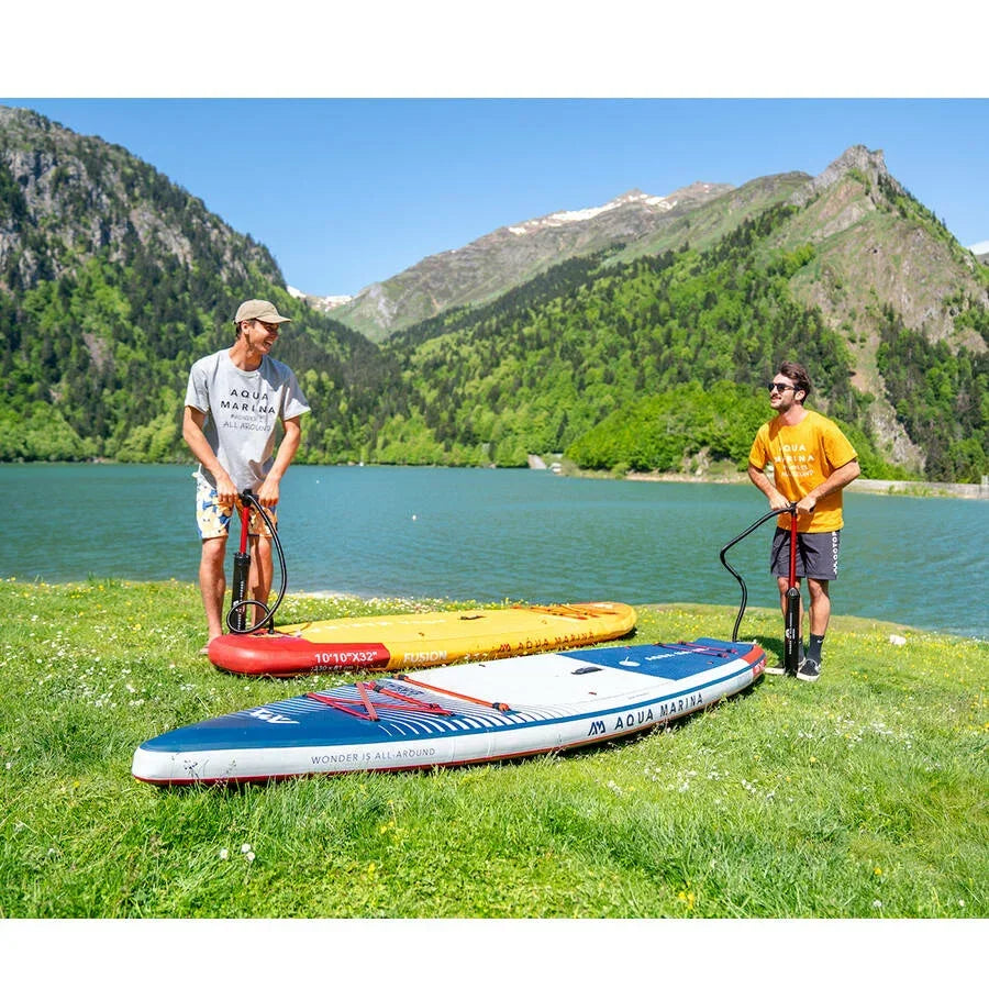 Göl kenarında şişme SUP board hazırlayan iki erkek, dağ ve doğa manzarasıyla