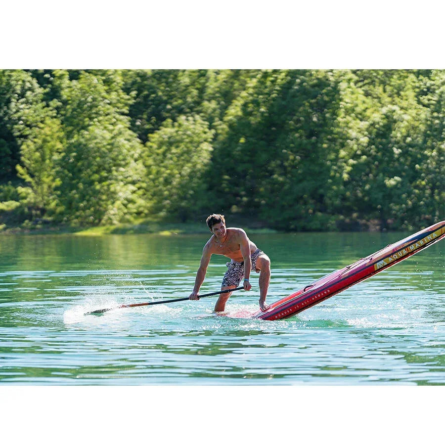 Doğada gölde Aqua Marina şişme SUP board üzerinde kürek çeken erkek, su sporları keyfi