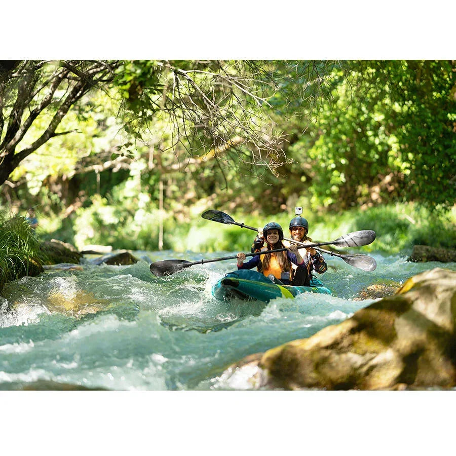 Doğada akarsuda iki kişi şişme kano ile kürek çekiyor, su sporları ve macera.