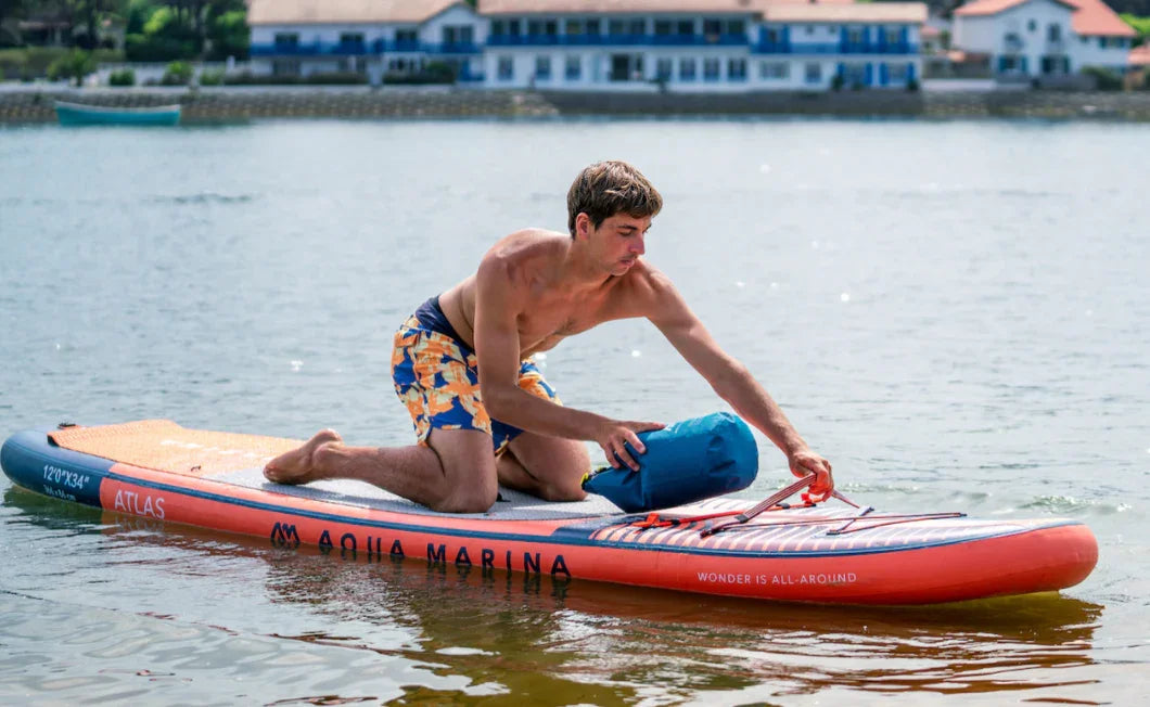Gölde Aqua Marina Atlas SUP şişme paddle board üzerinde diz çökmüş erkek, su sporları ekipmanı