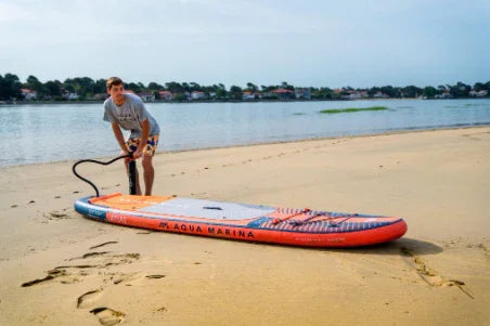 Kumsalda Aqua Marina Atlas şişme SUP paddle board şişiren erkek, göl kenarı manzarası