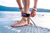 SUP board üzerinde ayak bileğine kayış takan kişi, gölde su sporu ekipmanı